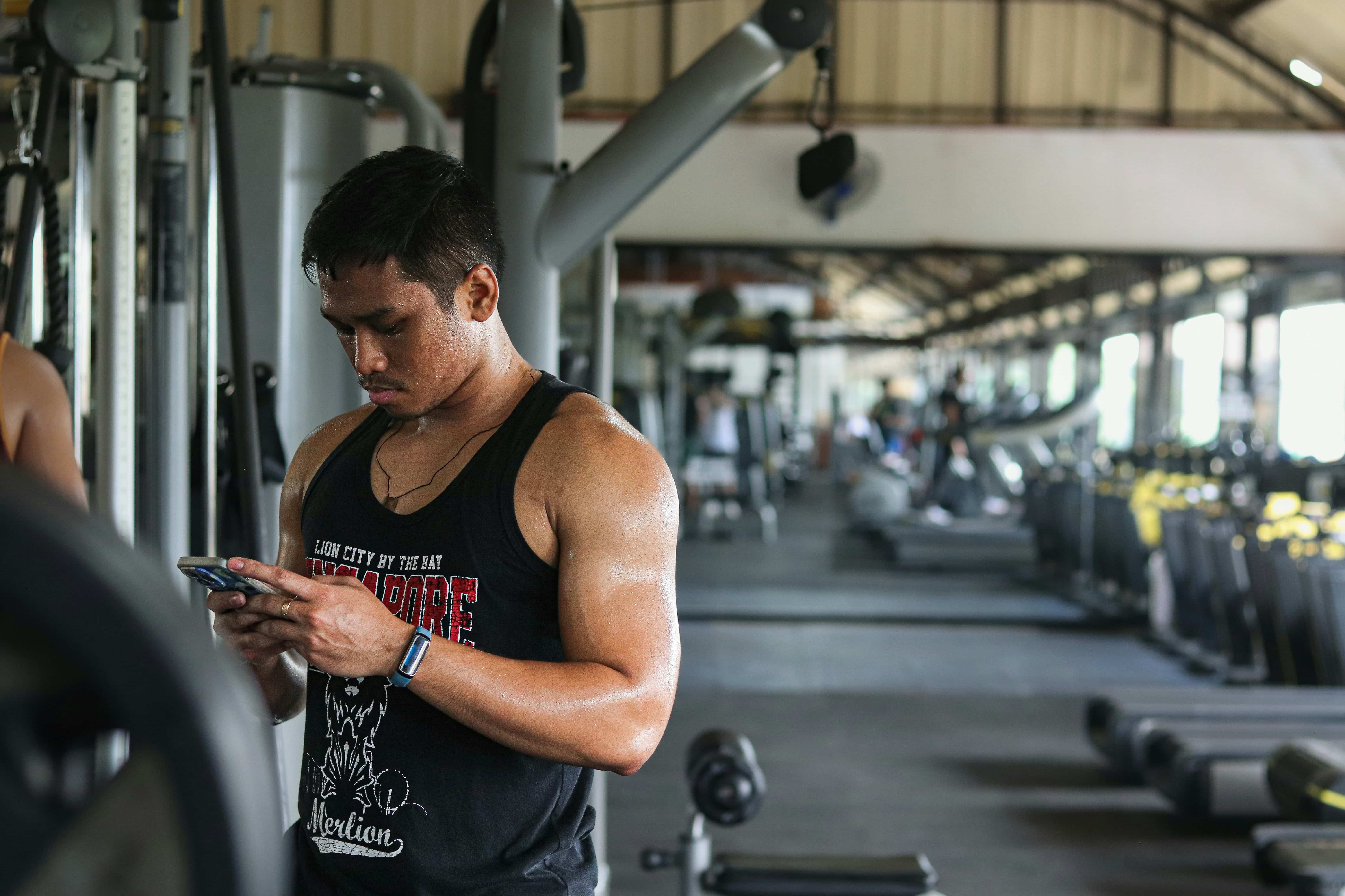 Man in a gym looking at his cell phone